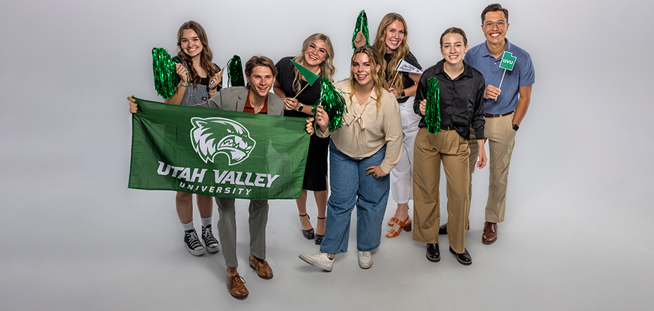 2023-24 Student Alumni Ambassadors smile and post with a UVU flag and pompoms.